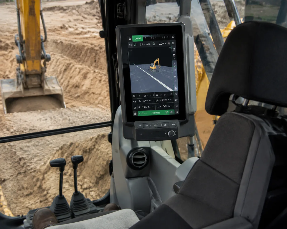 Excavator cab interior with machine guidance display screen